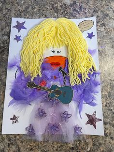 a doll made to look like a woman with yellow hair and purple feathers, holding a guitar