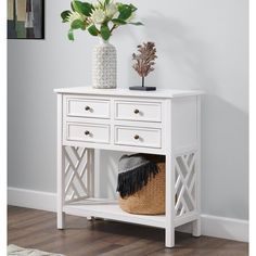 a white table with drawers and a basket on it next to a vase filled with flowers