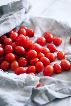 a bunch of red tomatoes sitting on top of a white table cloth covered in wax paper