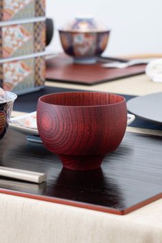 a wooden bowl sitting on top of a table next to other plates and bowls in the background