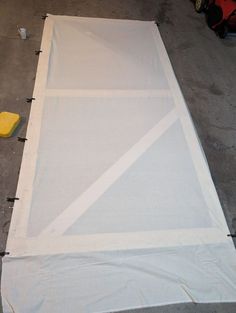 a piece of white fabric is being laid out on the floor to be used as an art project