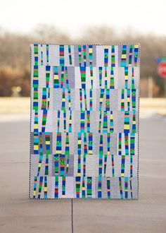 a colorful quilt is on the ground in front of a parking lot with no cars