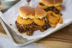 two sloppy joe sandwiches sitting on top of a white paper towel next to some sauce