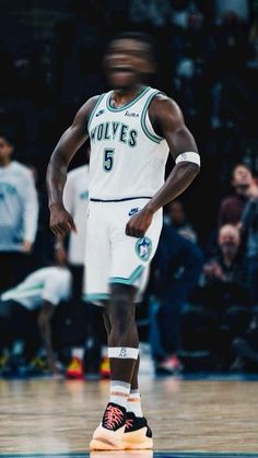 a man standing on top of a basketball court wearing a white jersey and green shorts