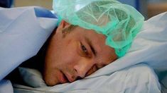 a man laying in bed wearing a surgical cap