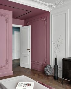 an empty living room with pink walls and white trim on the door, in front of a tv