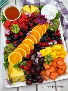 a platter filled with fruits and vegetables next to a cup of tea