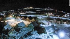 an aerial view of a town at night with snow on the ground and buildings lit up