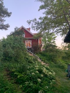 a red house sitting on top of a lush green hillside