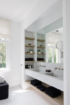 an image of a bathroom setting with white walls and flooring, including open shelving