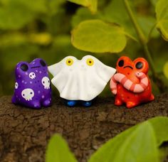 three small plastic toys sitting on top of a tree branch