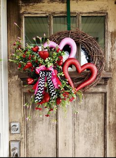 a wreath with two hearts hanging on the front door