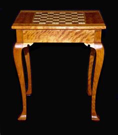 a small wooden table with chess board on it's top and legs, against a black background