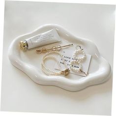 a white tray with pearls and jewelry on it