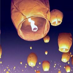 many lit up lanterns flying in the sky