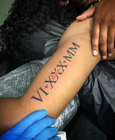 a woman is getting her arm tattooed with the word vixm on it and hearts