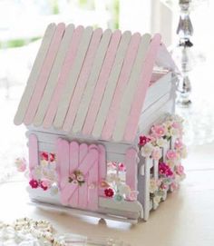 a pink and white dollhouse with flowers on the outside, sitting on a table