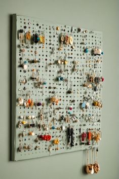 a peg board with lots of earrings hanging from it's sides on the wall