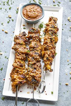 chicken skewers on a plate with dipping sauce