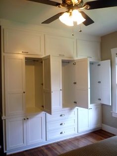 an empty bedroom with white cabinets and a ceiling fan