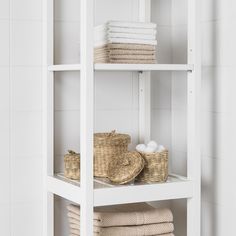 a white shelf with baskets and towels on it