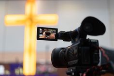 a video camera is being used to record a person's image in front of a cross