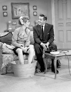 an old black and white photo of two people sitting on a couch talking to each other