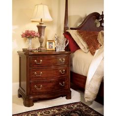 a bed room with a neatly made bed and a night stand next to a rug