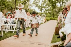 two young boys are walking down the aisle at a wedding ceremony with their cowboy hats on