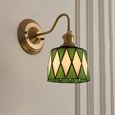 a green and white lamp hanging from a wall mounted light fixture on the side of a door