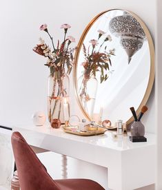 a white table topped with a mirror and vase filled with flowers