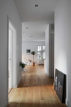 an empty hallway with white walls and wood floors