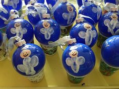 many blue ornaments with white bows and teddy bears on them are sitting on a table