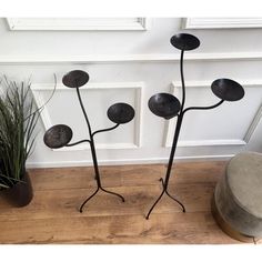 two metal flower sculptures sitting on top of a wooden floor next to a potted plant