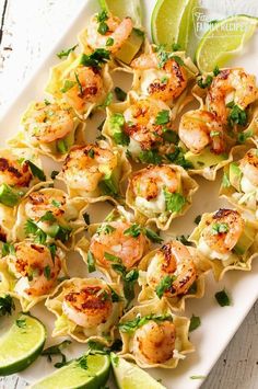 shrimp and tortilla shells with lime wedges on a white platter, ready to be eaten