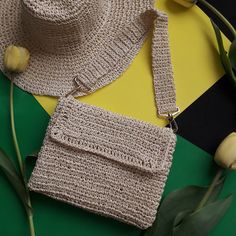 a crocheted purse sitting on top of a green and yellow table next to flowers