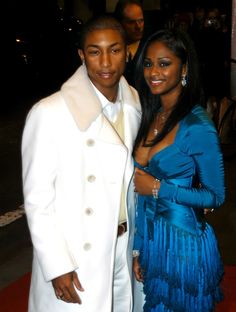 a man in a white suit and woman in a blue dress posing for the camera