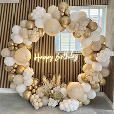 a happy birthday balloon arch with balloons and pineapples in front of a window