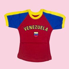 a red and blue soccer jersey with venezuela written on the chest, against a pink background