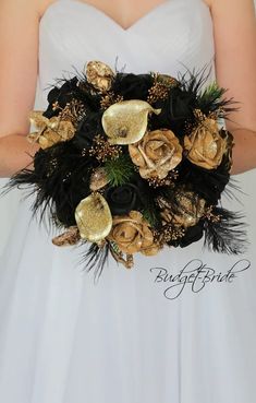 a bridal bouquet with gold and black flowers, feathers and pineconi leaves