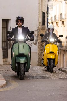 two people on motor scooters driving down the street