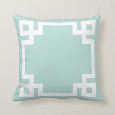 a white and blue pillow with a square design on the front, along with a light green border