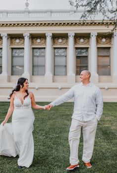 a bride and groom holding hands in front of a building