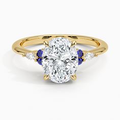 an oval shaped diamond and blue sapphire engagement ring with two side stones on the band