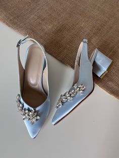 a pair of blue high heel shoes sitting on top of a white table next to a piece of cloth