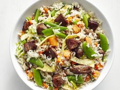 a white bowl filled with rice, meat and veggies on top of a table