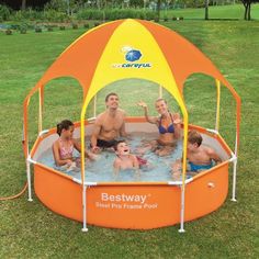 a group of people sitting in a swimming pool with an orange and yellow cover over it