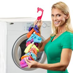 a woman is holding up some clothes in front of a washer and dryer