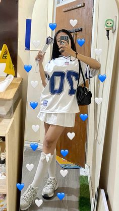 a woman taking a selfie in front of a mirror wearing a football uniform and holding a cell phone