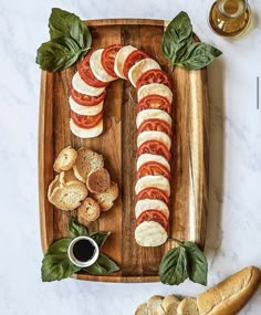 sliced tomatoes, mozzarella and basil on a wooden platter with garlic bread